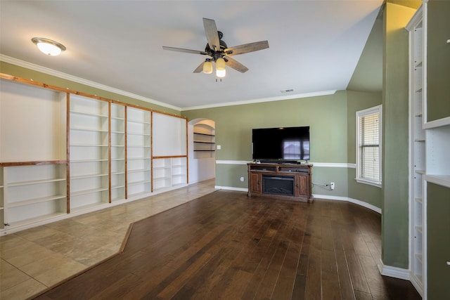 unfurnished living room with hardwood / wood-style flooring, visible vents, a ceiling fan, baseboards, and ornamental molding