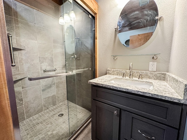 bathroom featuring a textured wall, a shower stall, and vanity