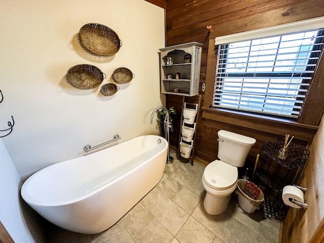 full bathroom with a freestanding tub, toilet, and wooden walls