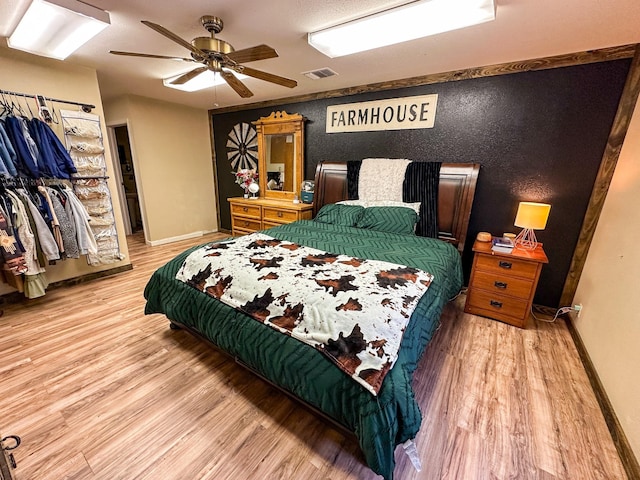 bedroom featuring ceiling fan, wood finished floors, visible vents, and baseboards