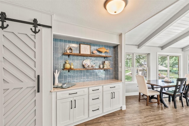 bar featuring beamed ceiling, backsplash, a textured ceiling, and wood finished floors