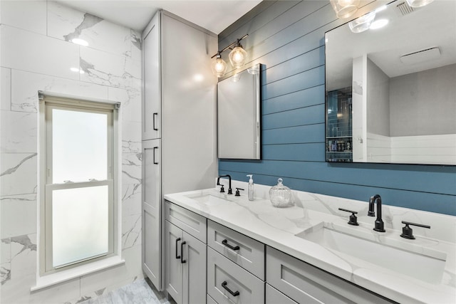 full bath featuring double vanity, marble finish floor, visible vents, and a sink