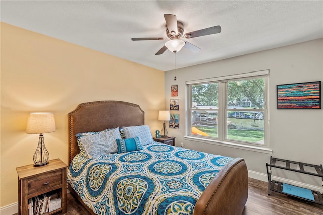 bedroom featuring ceiling fan, a textured ceiling, baseboards, and wood finished floors