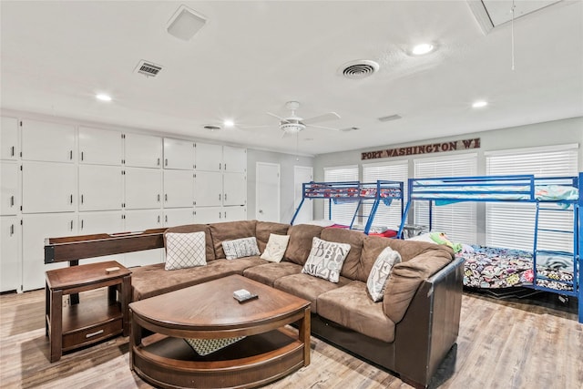 living room featuring light wood-type flooring, attic access, and visible vents