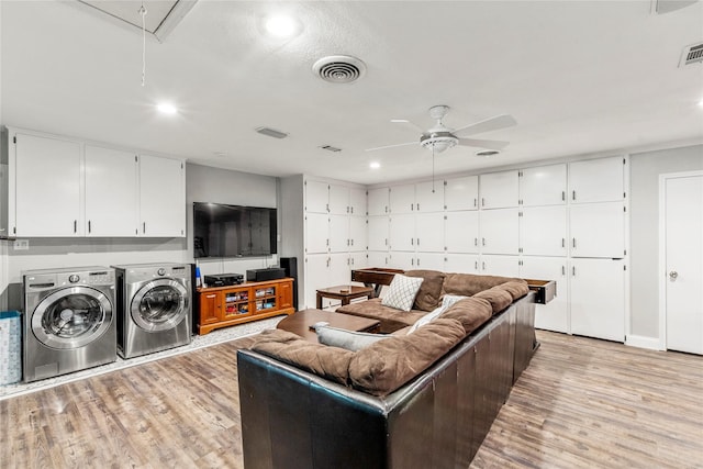 living room featuring washing machine and clothes dryer, visible vents, light wood-style flooring, attic access, and ceiling fan