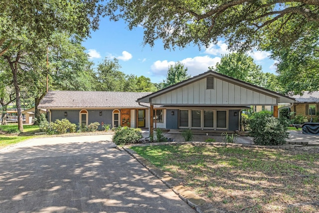 ranch-style house with board and batten siding, concrete driveway, and brick siding