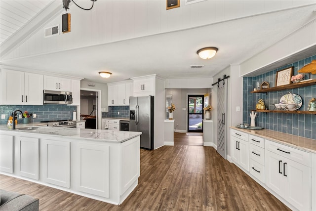 kitchen featuring a barn door, visible vents, appliances with stainless steel finishes, white cabinetry, and a sink