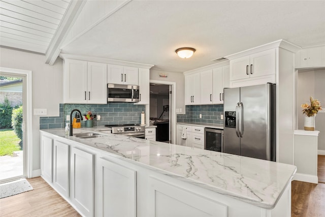 kitchen with visible vents, wine cooler, appliances with stainless steel finishes, a peninsula, and a sink