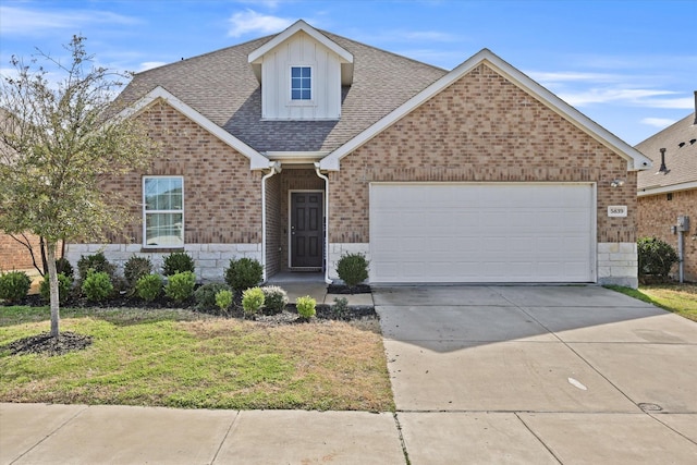 view of front facade with a front yard, stone siding, driveway, and an attached garage