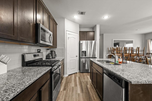 kitchen with appliances with stainless steel finishes, visible vents, a sink, and dark brown cabinets