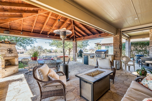 view of patio with area for grilling, fence, a gazebo, outdoor dining area, and an outdoor kitchen