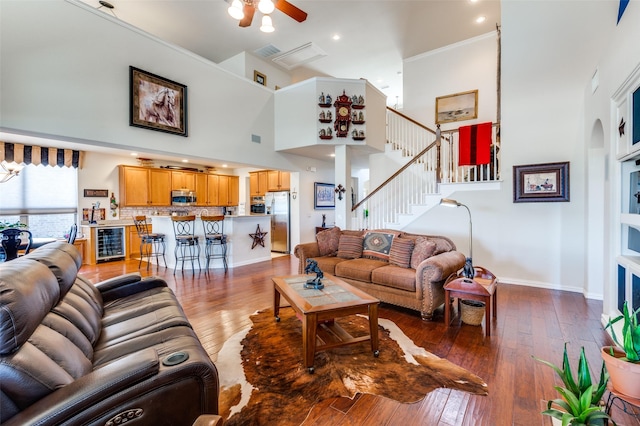 living area with visible vents, hardwood / wood-style floors, wine cooler, baseboards, and a towering ceiling