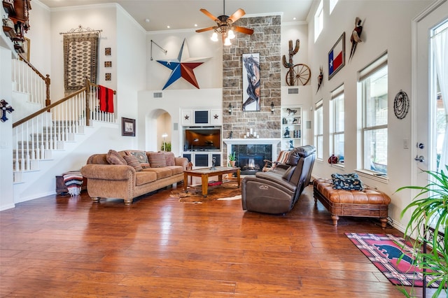 8912 Landmark Ln, Denton, TX 76207 - living room featuring a towering ceiling, a ceiling fan, hardwood / wood-style floors, stairs, and a fireplace