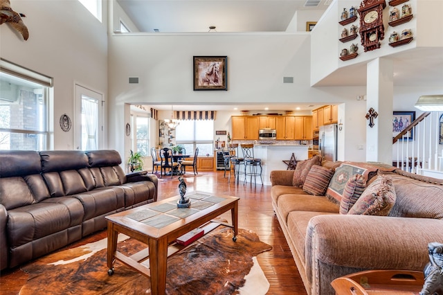 living room featuring hardwood / wood-style flooring, a high ceiling, and visible vents