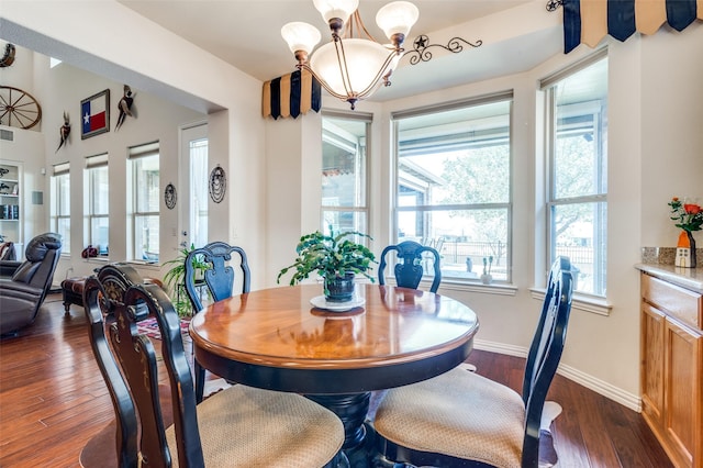 dining space with baseboards, an inviting chandelier, and dark wood finished floors