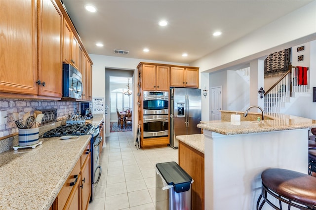 8912 Landmark Ln, Denton, TX 76207 - kitchen featuring stainless steel appliances, tasteful backsplash, light tile patterned floors, light stone counters, and recessed lighting