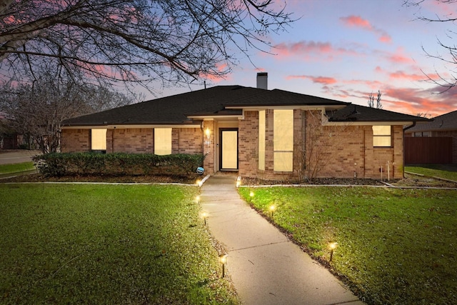 view of front of house featuring a front lawn, a chimney, fence, and brick siding