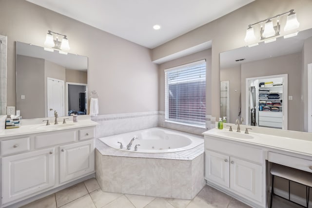 bathroom with two vanities, a sink, a jetted tub, and tile patterned floors