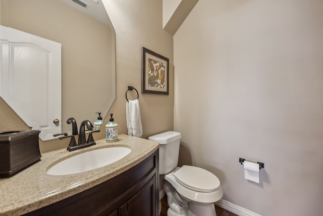 half bathroom with toilet, baseboards, visible vents, and vanity