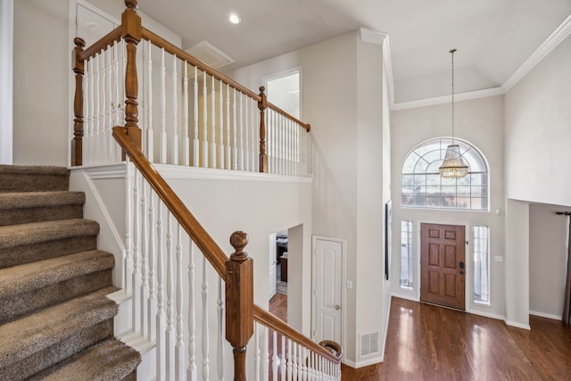 foyer featuring high vaulted ceiling, wood finished floors, visible vents, baseboards, and stairway