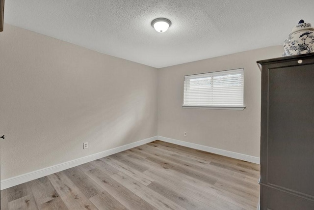 empty room featuring a textured ceiling, baseboards, and wood finished floors