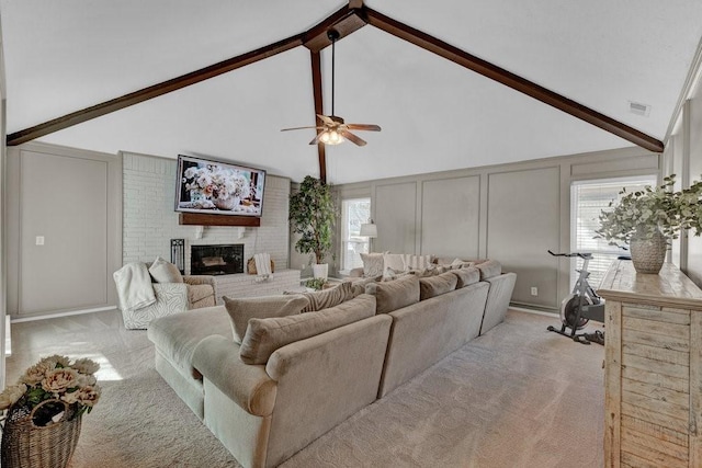 living area featuring a brick fireplace, light colored carpet, a decorative wall, and beamed ceiling