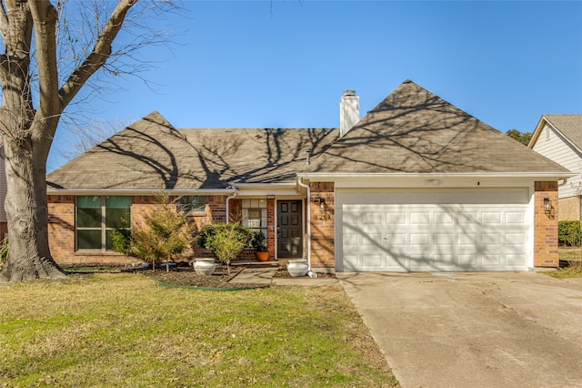 view of front of house featuring brick siding, a chimney, a front yard, a garage, and driveway