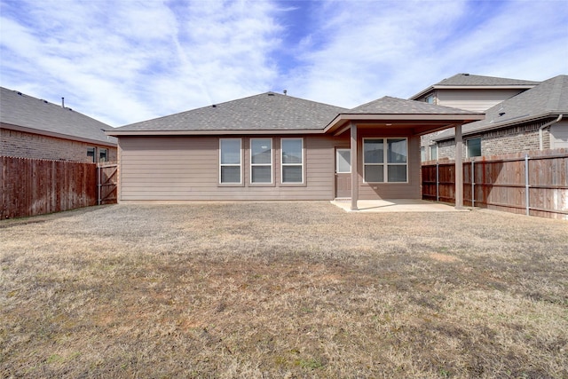 back of property with a patio, a yard, a shingled roof, and a fenced backyard