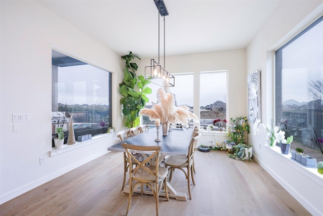 dining space with a notable chandelier, wood finished floors, and baseboards