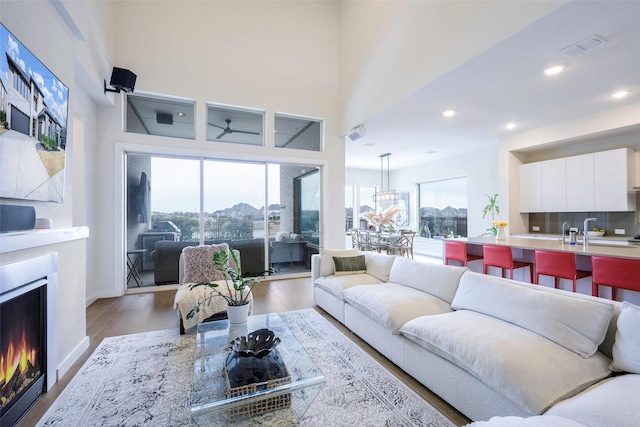 living room with recessed lighting, wood finished floors, visible vents, and a lit fireplace