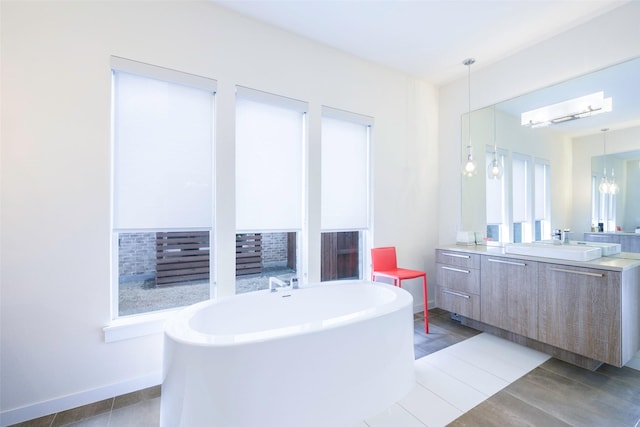 bathroom featuring tile patterned flooring, vanity, baseboards, and a freestanding tub