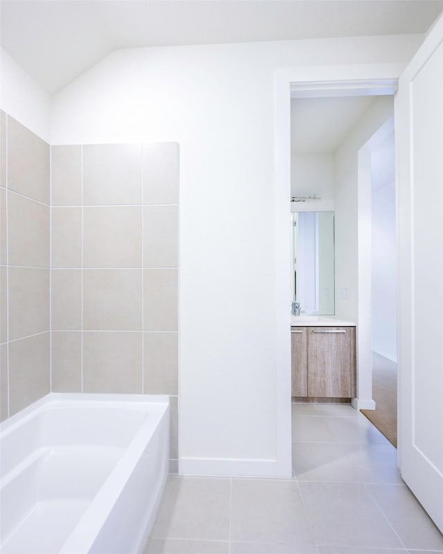 full bath featuring tile patterned floors, a washtub, baseboards, vanity, and vaulted ceiling