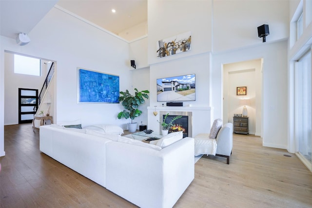 living area with light wood-style flooring, a fireplace, and a high ceiling