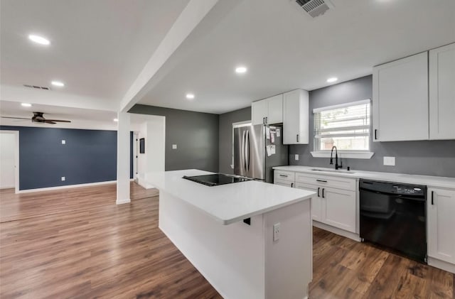 kitchen featuring black appliances, a kitchen island, a sink, and dark wood finished floors