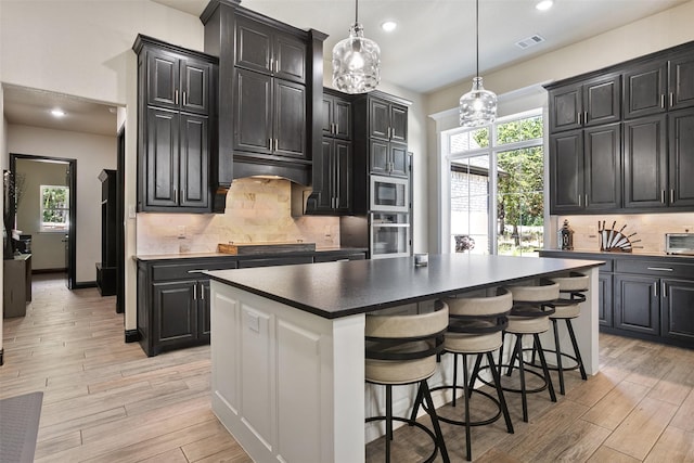 kitchen featuring appliances with stainless steel finishes, light wood-type flooring, and dark cabinets