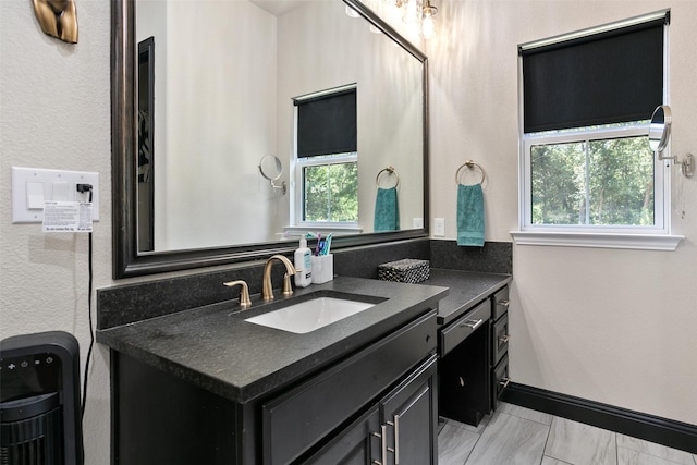 bathroom with marble finish floor, vanity, a wealth of natural light, and baseboards