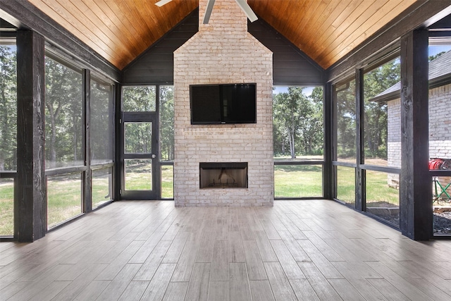 unfurnished sunroom featuring vaulted ceiling, wooden ceiling, and a brick fireplace