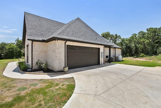 view of home's exterior featuring brick siding, a shingled roof, a lawn, an attached garage, and driveway