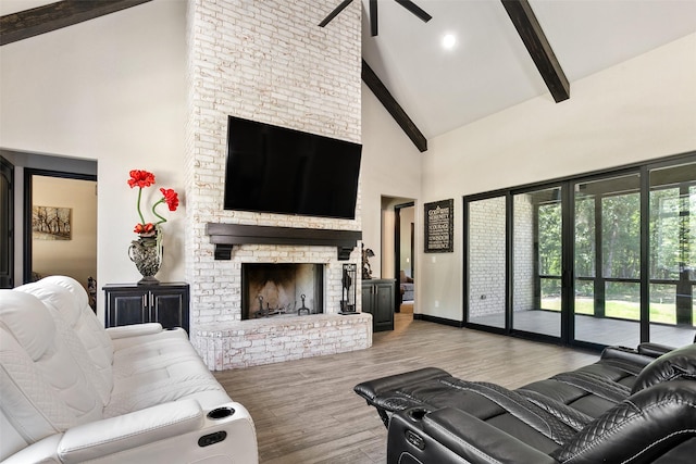 living area with high vaulted ceiling, wood finished floors, baseboards, a brick fireplace, and beamed ceiling