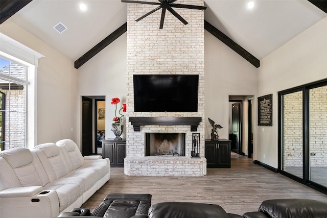 living area featuring beamed ceiling, a brick fireplace, and wood finished floors