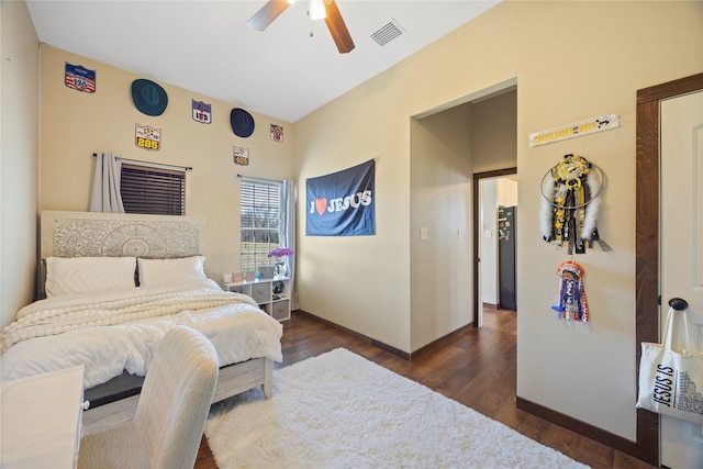 bedroom featuring visible vents, dark wood-type flooring, freestanding refrigerator, ceiling fan, and baseboards