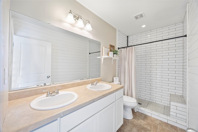 bathroom with visible vents, a sink, and a tile shower