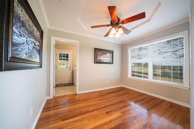 spare room with crown molding, light wood-style flooring, and baseboards