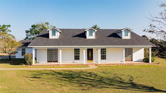 cape cod house featuring covered porch, a shingled roof, and a front yard