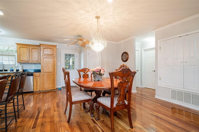 dining room featuring a healthy amount of sunlight, crown molding, visible vents, and wood finished floors