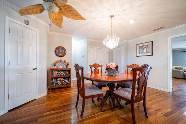 dining room featuring hardwood / wood-style flooring, ceiling fan with notable chandelier, visible vents, baseboards, and ornamental molding