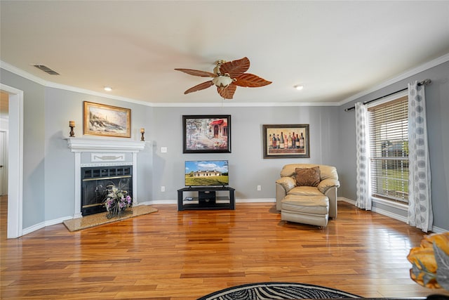 living area with baseboards, visible vents, crown molding, light wood-type flooring, and a fireplace