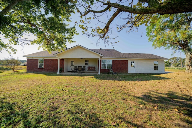 rear view of property with brick siding, a patio, and a lawn