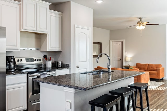 kitchen featuring appliances with stainless steel finishes, a breakfast bar, wood finished floors, a kitchen island with sink, and a sink