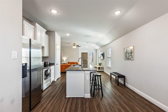 kitchen with a breakfast bar area, dark wood-type flooring, a sink, white cabinetry, and appliances with stainless steel finishes